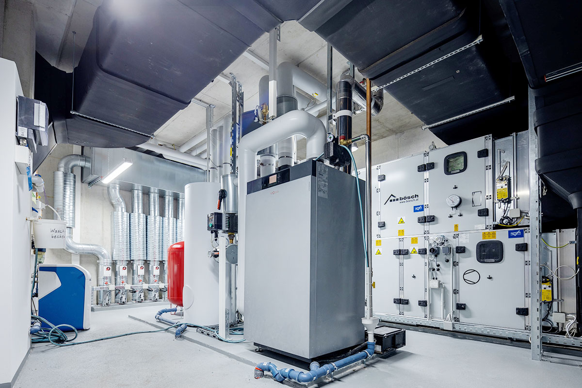 Technikraum mit Gas-Brennwertkessel, Pufferspeicher und Membranausdehnungsgefäß und im Hintergrund der RLT-Anlage Technikraum mit Gas-Brennwertkessel, Pufferspeicher und Membranausdehnungsgefäß und im Hintergrund der RLT-Anlage